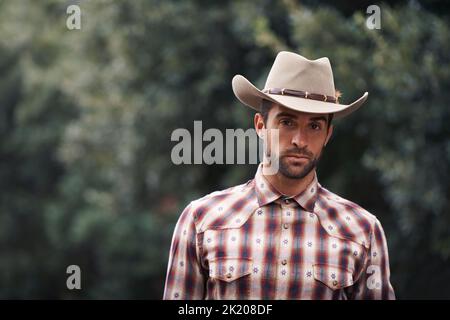 Lo stile non sarà mai applaiato. Ritratto di un bell'uomo che indossa una camicia da assegno e un cappello da cowboy. Foto Stock