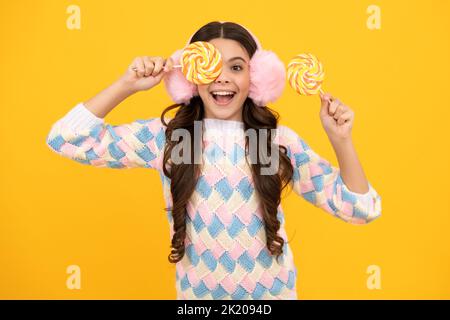 Bambino teen freddo con lollipop sopra sfondo isolato giallo. Dolce vita d'infanzia. Ragazza teen con caramella lollipop yummy. Foto Stock