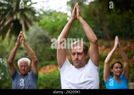 Focus and Breathe. Un giovane che conduce un esercizio di respirazione in una classe di yoga all'aperto. Foto Stock