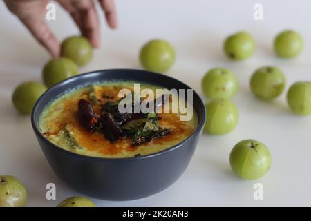 Curry Nellika. Il curry di uva spina di cocco in stile Kerala è fatto di uva spina fresca, cocco macinato e spezie. Ripresa su sfondo bianco. Foto Stock