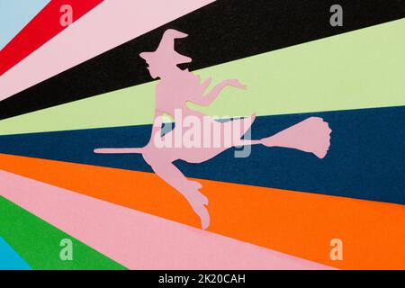 silhouette rosa di una strega che vola su una scopa su un colorato sfondo artistico, creativo concetto di halloween, piatto, carta artigianale Foto Stock