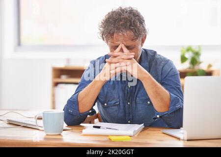 Estremamente stanco di venerdì... un uomo d'affari maturo che guarda stanco mentre lavora alla sua scrivania. Foto Stock
