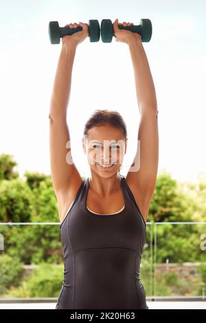 Allenarsi a casa batte la palestra ogni giorno. Ritratto di una giovane donna sportiva che lavora con i manubri. Foto Stock