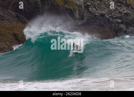 Un surfista nel surf a Kynance Cove sulla penisola di Lizard, Cornovaglia, Inghilterra Foto Stock