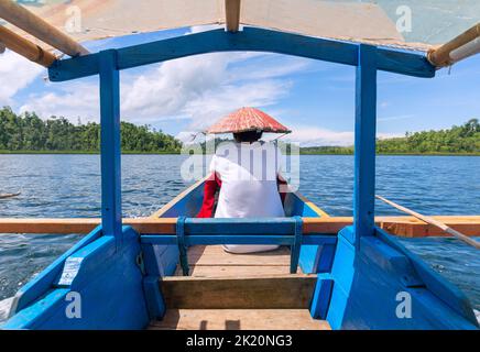 Pescatore locale seduto su una tradizionale barca da pesca sulla spiaggia Togean, Bali, Indonesia. Foto Stock