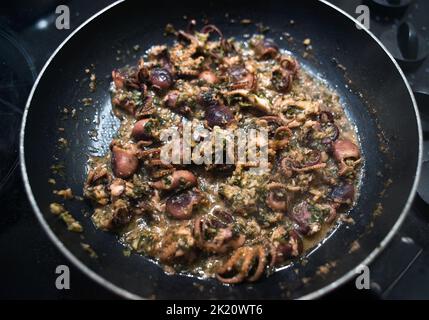 Polpo fritto in padella con aglio e prezzemolo Foto Stock