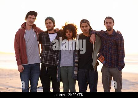 Non ci torneremo, un gruppo di amici che camminano lungo una spiaggia al tramonto. Foto Stock