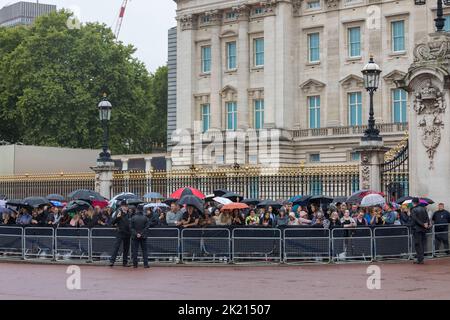 Le folle aspettano alle porte di Buckingham Palace per arrivare sotto la pioggia. La nazione continua a piangere la morte della Regina Elisabetta II Immagine ripresa Foto Stock