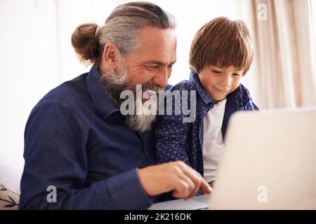 Aiutare il nonno a configurare il suo nuovo notebook. Nonno e nipote che utilizzano un notebook insieme. Foto Stock