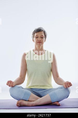 Trovare equilibrio. Scatto completo di una donna attraente meditating mentre fa yoga. Foto Stock