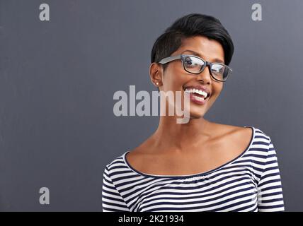 Ceneri anca. Ritratto di una giovane donna felice in piedi su uno sfondo grigio. Foto Stock