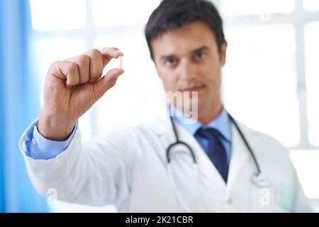 Una pillola per guarirli tutti. Un bel giovane medico che tiene in mano una compressa di capsule. Foto Stock