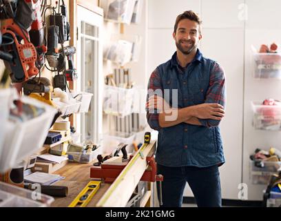 Mi chiami, onorevole Fixit. Ritratto di un bel giovane handyman in piedi davanti ai suoi utensili da lavoro. Foto Stock