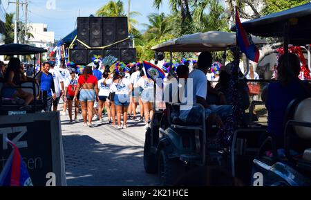 La parte posteriore di un galleggiante con enormi diffusori seguiti da festaioli e golf cart nella processione di San Pedro, Belize Carnival 2022. Foto Stock