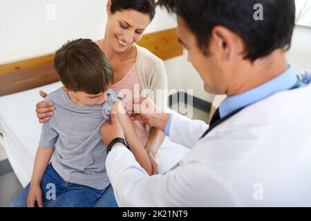 Heres un distintivo di coraggio per mostrare ai tuoi amici. Una madre che guarda suo figlio essere preso cura di suo medico. Foto Stock