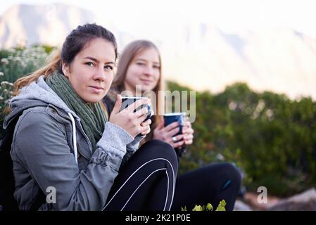 Non c'è niente di meglio di un caffè fresco in montagna: Due giovani donne allettanti si gustano bevande calde mentre si fa un'escursione. Foto Stock