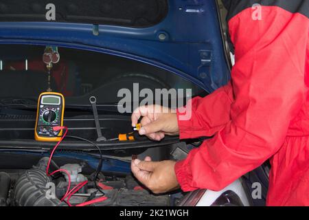 Mani di un elettricista auto che cambia i fusibili su un'auto guasta. Lavori meccanici ed elettronici sulle automobili Foto Stock
