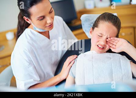 Tutti hanno una cavità ad un certo punto. Una bambina piangendo seduta in una sedia dei dentisti. Foto Stock