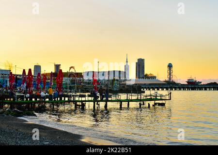 Batumi, Georgia - 25th novembre 2021: Cameriere con i clienti in ristorante di pesce sulla terrazza con tavoli e vista panoramica sul lungomare di Batumi in Georgia. Foto Stock