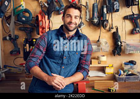 Se il suo rotto Ill ripararlo. Ritratto di un bel giovane handyman in piedi davanti ai suoi utensili da lavoro. Foto Stock