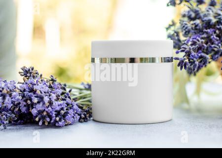 Crema corpo bianca mockup con fiori di lavanda, cosmetici per la cura della pelle. Crema idratante alla lavanda. Vuoto per la pubblicità Foto Stock