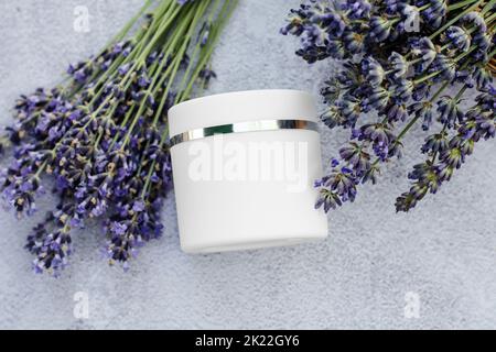 Crema corpo bianca mockup con fiori di lavanda, cosmetici per la cura della pelle. Crema idratante alla lavanda. Vuoto per la pubblicità Foto Stock