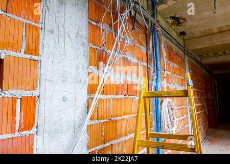 Scale per facilitare l'installazione dei cavi, scatole di distribuzione per l'elettricità. Un mazzo di cavi sono appesi al soffitto, passando tra i piani i. Foto Stock