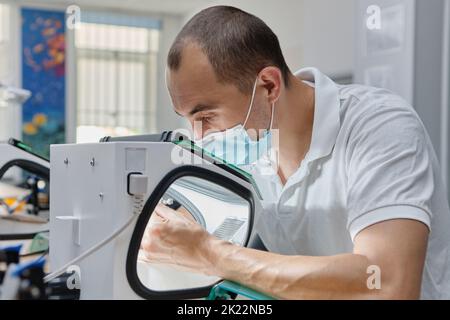 Dentista mulini a mano corone di denti creato su 3D stampante per metallo. Tecnico odontoiatrico che lavora con corone in ceramica in scatola protettiva presso il laboratorio. Foto Stock