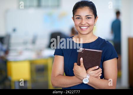 Ive ha sempre avuto il mio programma a portata di mano. Ritratto di una giovane donna d'affari attraente che tiene il suo giornale mentre si trova in un ufficio. Foto Stock