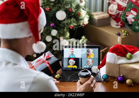 Sorridente bel giovane ama decorare l'albero di Natale mentre tiene un tablet per videochiamare a casa. Solo per celebrare il nuovo anno. Foto Stock