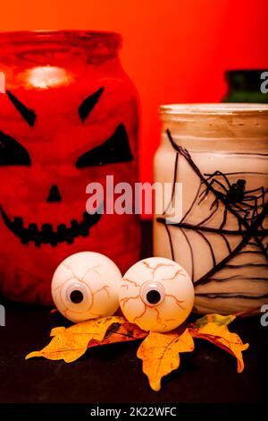 Halloween composizione di occhi, zucca e un vaso con un ragno Foto Stock