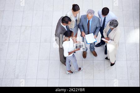 Un team aziendale diversificato che discute della documentazione in una riunione. Foto Stock