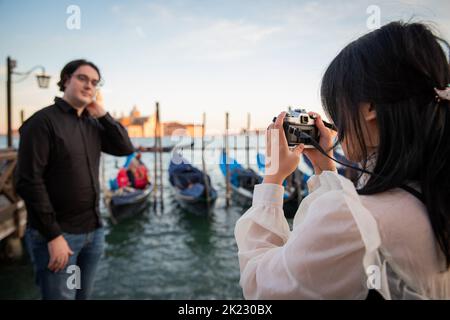 La ragazza scatta una foto del suo ragazzo mentre sono in vacanza a Venezia, turisti in visita alla città dell'amore Foto Stock