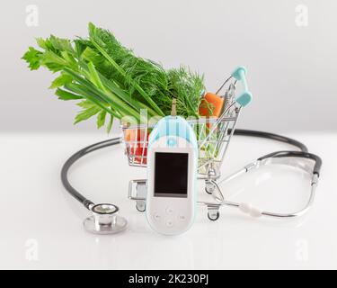 Verdure biologiche in un carrello con glucometro e stetoscopio su un tavolo bianco. Dieta vegetariana, la dieta migliore per il diabete. Concetto di no dia Foto Stock