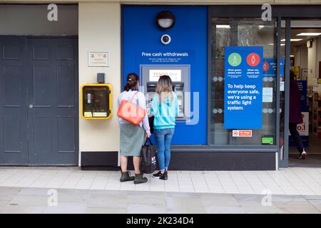 Vista esterna del negozio Tesco Extra clienti che utilizzano un bancomat fuori dal negozio di alimentari a Tenby Pembrokeshire South Wales UK Foto Stock