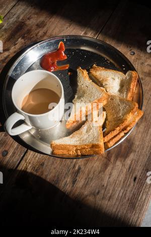 Toast al burro alla griglia servito con una tazza di tè caldo indiano e un ketchup di pomodoro sul lato. Uttarakhand , India. Foto Stock