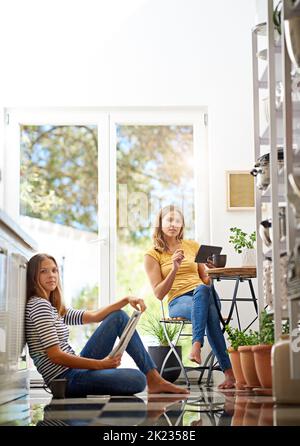 Relax in cucina. Ritratto di sorelle gemelle che si rilassano insieme nella loro cucina. Foto Stock