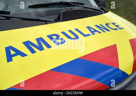 Logo Dutch Ambulance sul cappuccio di un furgone medico parcheggiato. Cartello di ambulanza su veicolo giallo con strisce rosse e blu. Foto Stock