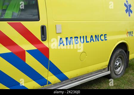 Logo Dutch Ambulance sul lato di un furgone medico parcheggiato. Cartello di ambulanza su veicolo giallo con strisce rosse e blu. Foto Stock