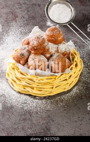 Le palle di olio Oliebollen olandesi sono anche talvolta chiamate ciambelle olandesi o palle di pasta olandesi closeup nel cestello sul tavolo. Verticale Foto Stock