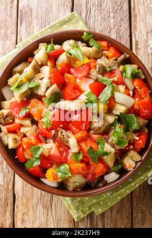 Insalata di melanzane arrosto kozlenmis patl?Can salate? con peperoni arrostiti, cipolle, pomodori e spicchio d'aglio nel recipiente sul tavolo. Verticale in alto v Foto Stock