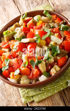 Insalata di melanzane arrosto kozlenmis patl?Can salate? con peperoni arrostiti, cipolle, pomodori e spicchio d'aglio nel recipiente sul tavolo. Verticale Foto Stock