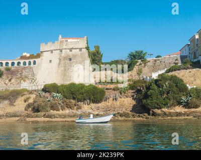 Vista del forte medievale Forte de Sao Clemente sul fiume Mira con una piccola barca nelle giornate di sole con cielo azzurro. Vila Nova de Milfontes, Portogallo Foto Stock