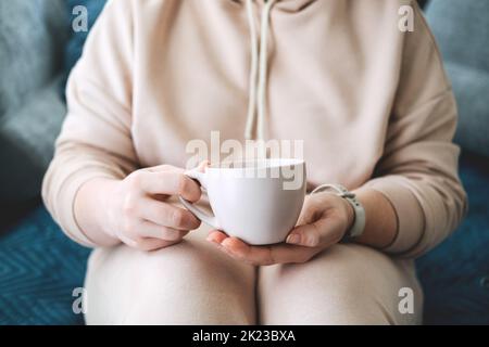 Cura di sé, soggiorno a casa, atmosfera accogliente. Prendetevi cura di voi stessi, concetto di Amore voi stessi. Donna mani con tazza di bevanda calda a casa Foto Stock