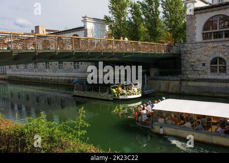 Lubiana, Slovenia - Settembre 3rd 2022. Le barche turistiche passano sotto il Ponte dei macellai attraversando il fiume Ljubljanici nel centro di Ljubljana, in Slovenia. Foto Stock