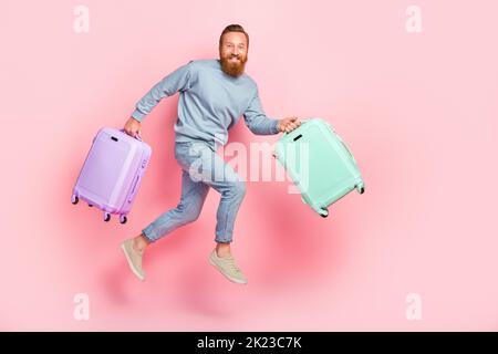 Profilo a lunghezza intera ritratto di persona pazza braccia tenere valigia fretta salto isolato su sfondo di colore rosa Foto Stock