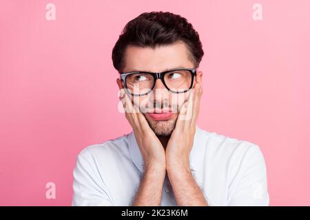 Primo piano foto di giovane bello infelice grimace annoiato touch occhiali faccia stressato hanno problemi di lavoro manager guardare spazio vuoto isolato sul colore rosa Foto Stock