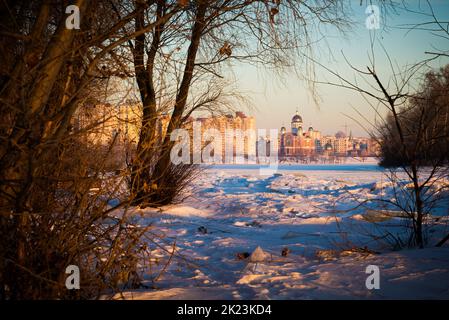 La moderna Cattedrale di intercessione della Madre di Dio, con cupole dorate, vicino al fiume Dnieper ghiacciato all'alba Foto Stock