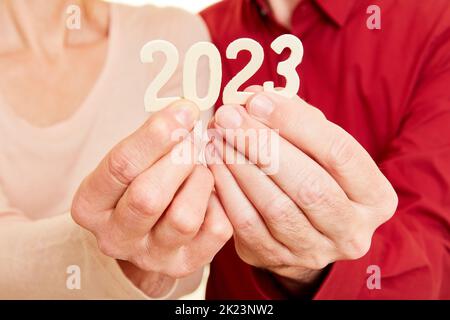 Due mani anziane mostrano l'anno 2023 come un numero Foto Stock