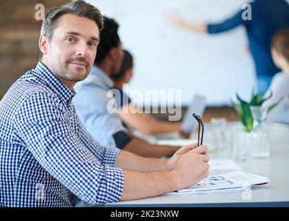 Stare al passo con la curva creativa del business. Un designer maturo che sorride alla macchina fotografica in una sala riunioni. Foto Stock